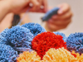 Bunches of homemade pom poms with maker in background