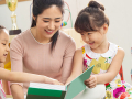 Young female teacher, volunteer reads to a group of smiling young kids