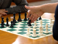 a game of chess being played by two players on a wooden table