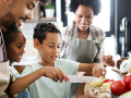 family of four cutting vegetables together with smiles on their faces