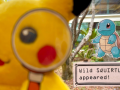 A pikachu plush with a magnifying glass searches for clues, with a Squirtle image seen behind it.