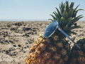 A pineapple at the beach, wearing sunglasses.
