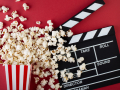 Popcorn and a clapper board on the red background