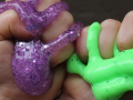 two hands squishing purple and green-lime slime.