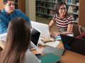 A group of five students sitting around a table with their computers.