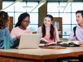 A group of diverse teens in a library with study materials, they are smiling and collaborating.