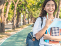 Female student on a college campus holding writing materials.