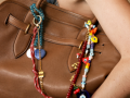 In the picture is a woman's hand holding a tote bag decorated with bead bag charms