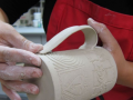 A person is making a ceramic mug. 