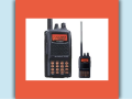 Two black HAM radios with orange screens and antennae sit next to each other on a white background.