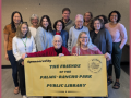 people standing with friends of the library sign