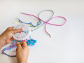 hands hold a foam kumihimo disk and there are braids demonstrating the technique