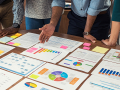 people leaning over a table looking at business spreadsheets