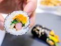 close up of a hand holding a kimbap roll