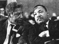 two men in black suits and ties sitting next to each other