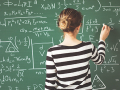 Girl working math on green chalkboard