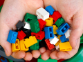 Child’s hands holding colorful LEGO-type building bricks.