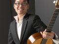 A man holding a guitar and looking at the camera