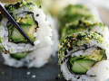Multiple pieces of sushi with avocado on a black slab board
